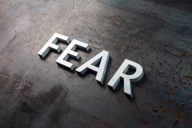 the word fear laid with silver letters on raw rusted steel sheet surface in diagonal slanted composition clipart