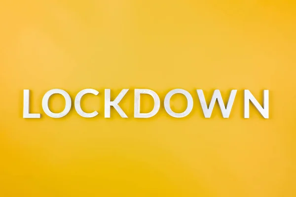 คําว่า lockdown วางด้วยตัวอักษรโลหะอลูมิเนียมแปรงบนพื้นหลังสีเหลือง — ภาพถ่ายสต็อก