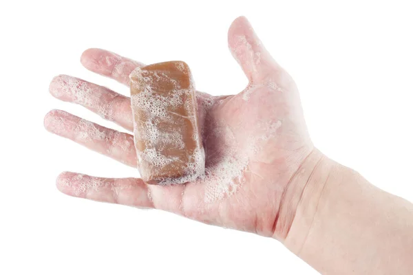 A wet piece of brown tar soap in human hand isolated on white background — Stock Photo, Image