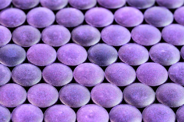 Close-up background of many purple organic compacted powder tablets laid tight in one layer on flat surface — Stock Photo, Image