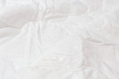 Beyaz kumaş battaniyesi, seçici odak ve arka plan bulanıklığı olan büyük bir yakın plan. Küçük beyaz kareler desen.