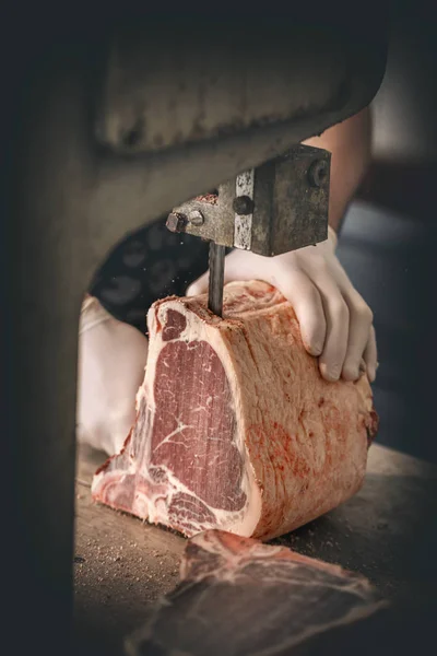 肉屋は、牛の肉を切っています。 ストックフォト