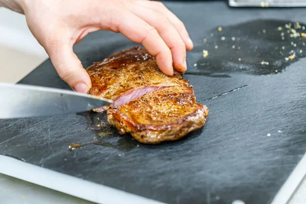 Il cuoco taglia la carne di maiale fritta — Foto Stock