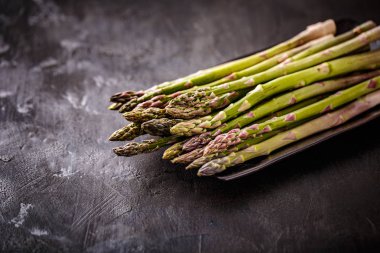 Siyah arka plan üzerine yatay biçimde taze çekilmiş aspargus
