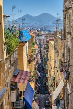 Small alleyway in the old town of Naples with Mount Vesuvius in the back clipart