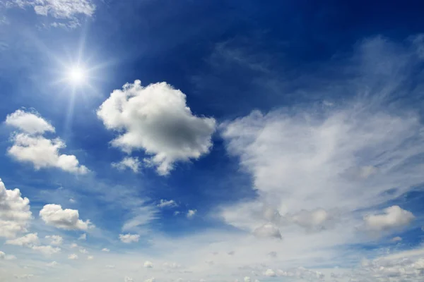 Jasne słońce i białe chmury na tle niebieskiego nieba. — Zdjęcie stockowe