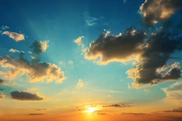 Heller Sonnenuntergang am blauen Himmel mit dunklen Wolken. — Stockfoto