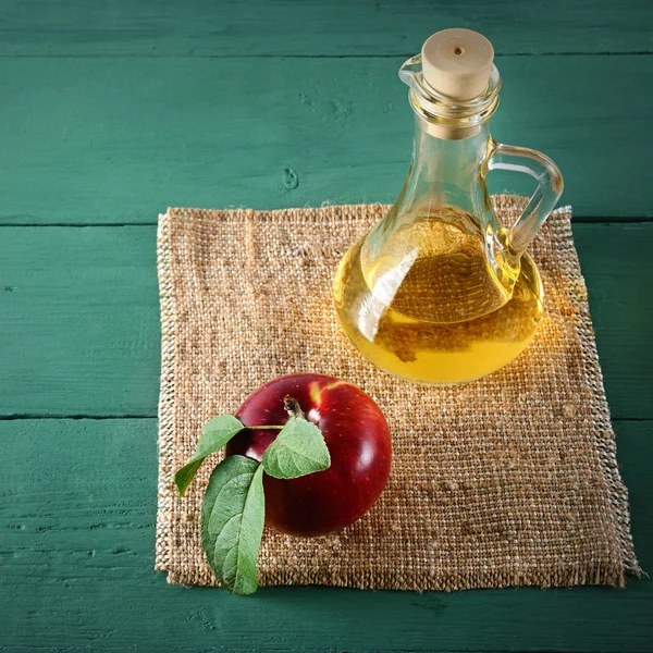 Vinaigre de cidre de pomme et pommes rouges mûres sur fond de bois vert — Photo