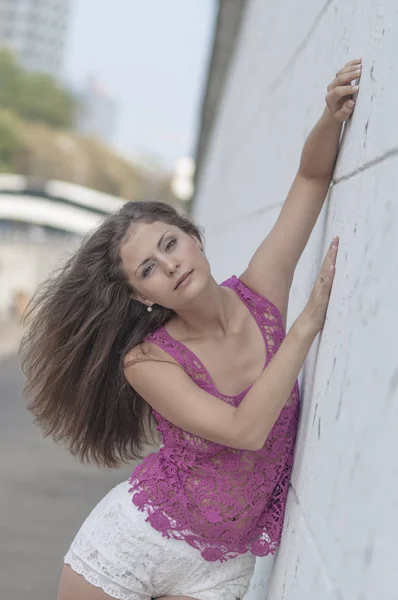 Mooie langharige meisje in transparante top en poseren is tegen een muur — Stockfoto