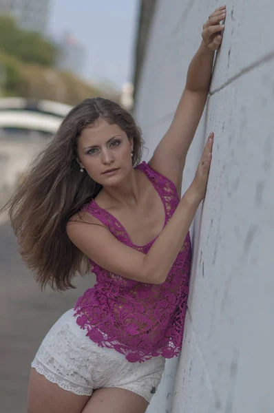 Vacker långhårig flicka i transparent topp och poserar mot en vägg — Stockfoto