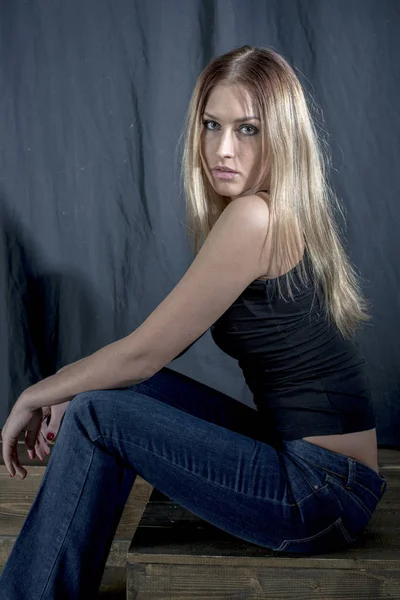 Jonge slanke blonde meisje in jeans en t-shirt poseren coquettishly — Stockfoto