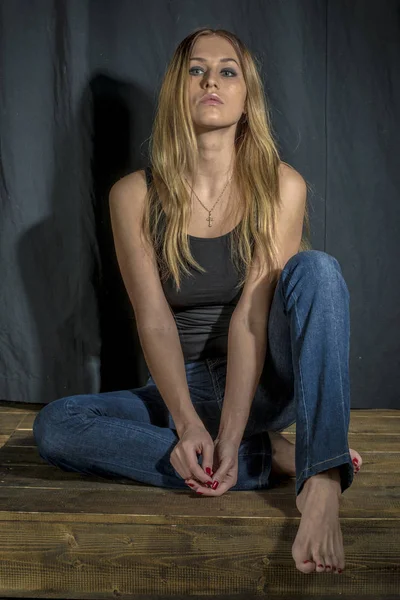 Young slender blonde girl in jeans and shirt posing coquettishly — Stock Photo, Image