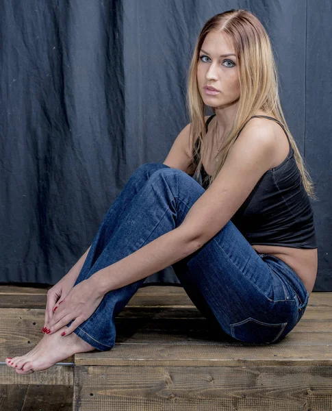 Joven chica rubia delgada en jeans y camisa posando coqueta —  Fotos de Stock