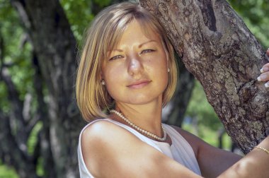 Bahar bahçe ağacında duran genç sarışın kadın