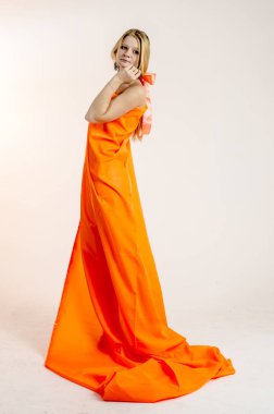 Parlak bir turuncu kumaş elbise genç güzel sarışın kadın