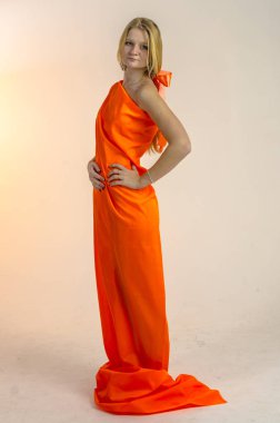 Parlak bir turuncu kumaş elbise genç güzel sarışın kadın