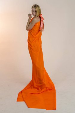 Parlak bir turuncu kumaş elbise genç güzel sarışın kadın