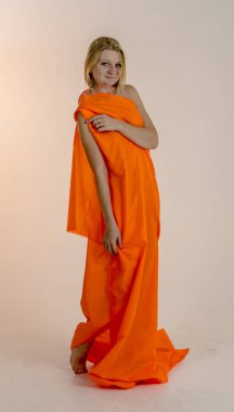 Parlak bir turuncu kumaş elbise genç güzel sarışın kadın