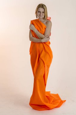 Parlak bir turuncu kumaş elbise genç güzel sarışın kadın