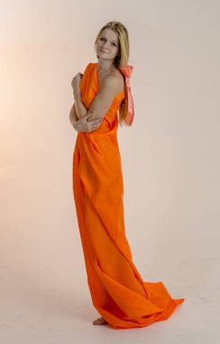 Parlak bir turuncu kumaş elbise genç güzel sarışın kadın