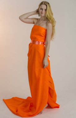 Parlak bir turuncu kumaş elbise genç güzel sarışın kadın