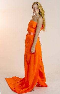 Parlak bir turuncu kumaş elbise genç güzel sarışın kadın