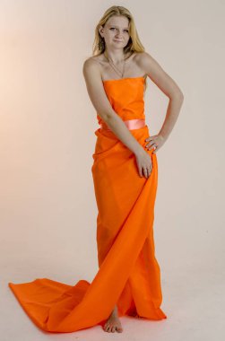 Parlak bir turuncu kumaş elbise genç güzel sarışın kadın