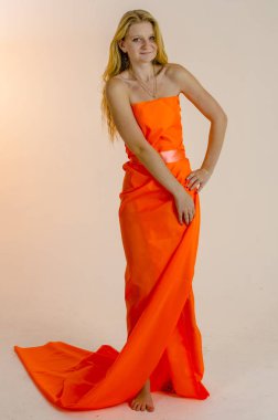 Parlak bir turuncu kumaş elbise genç güzel sarışın kadın