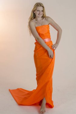 Parlak bir turuncu kumaş elbise genç güzel sarışın kadın