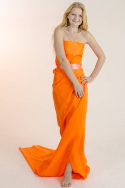 Parlak bir turuncu kumaş elbise genç güzel sarışın kadın