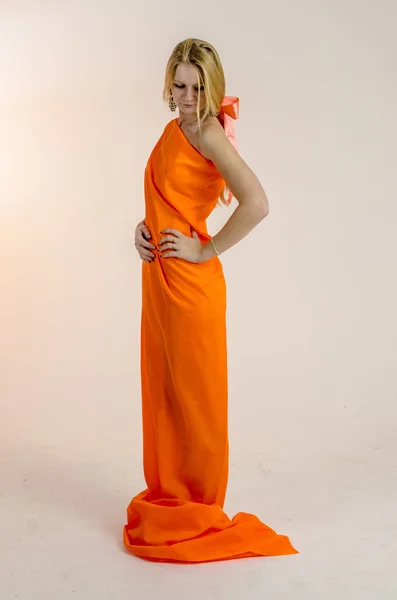 สาวสวย สาวผมบลอนด์ในผ้าสีส้มสดใสในชุด — ภาพถ่ายสต็อก