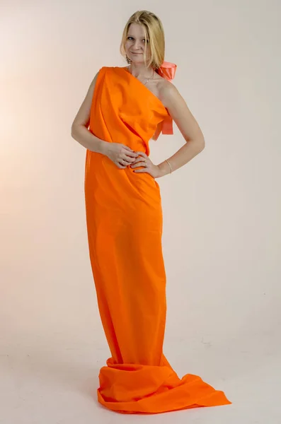 ドレスの明るいオレンジ色のファブリックで若い美しいブロンドの女性 — ストック写真
