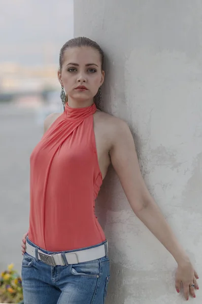 Joven chica rubia hermosa en una blusa roja de verano y jeans posando flexible —  Fotos de Stock