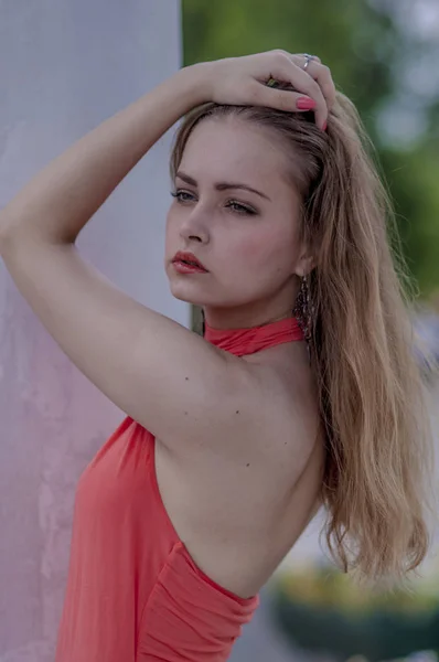 Ung, vakker, blond jente i rød sommerbluse og dongeribukser som er fleksible – stockfoto