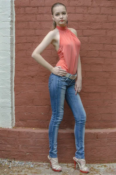 Joven chica rubia hermosa en una blusa roja de verano y jeans posando flexible — Foto de Stock