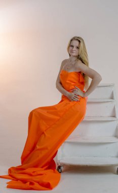 Parlak bir turuncu kumaş elbise genç güzel sarışın kadın