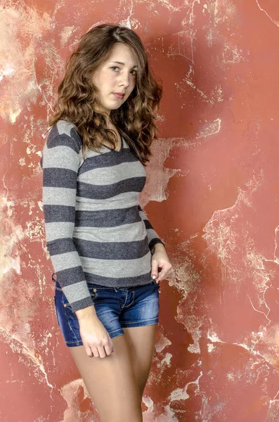 Young cheerful girl in denim shorts and a striped sweater walking in the youthful style — Stock Photo, Image