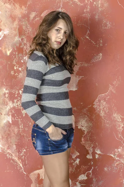 Genç neşeli kız kot şort ve genç tarzda yürüyüş çizgili süveter