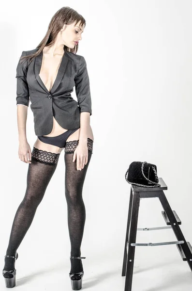 Young go go girl with a beautiful figure in a trendy black dress in skin-tight jacket and black high heels and platform with stockings dressed for a party with bag — Stock Photo, Image