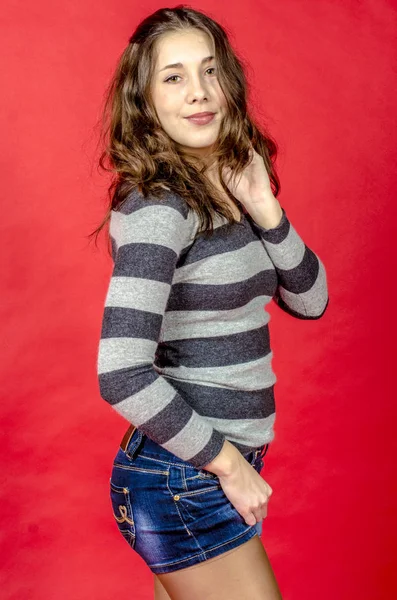 Young cheerful girl in denim shorts and a striped sweater walking in the youthful style — Stock Photo, Image