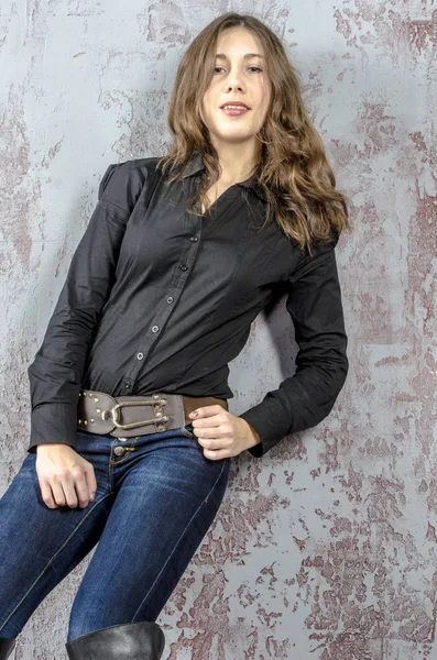 Jeune fille aux cheveux bouclés dans une chemise noire, jeans et bottes hautes style western cow-boy — Photo