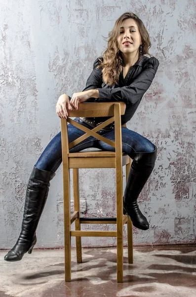 Young girl with curly hair in a black shirt, jeans and high boots cowboy western style — Stock Photo, Image