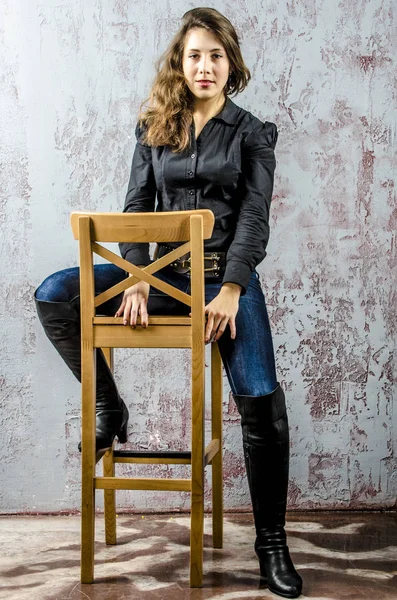 Молодая девушка с вьющимися волосами в черной рубашке, джинсах и высоких сапогах ковбойского западного стиля — стоковое фото