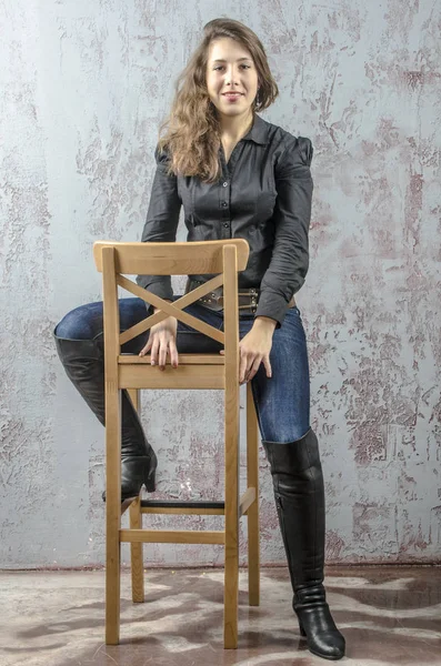 Молодая девушка с вьющимися волосами в черной рубашке, джинсах и высоких сапогах ковбойского западного стиля — стоковое фото
