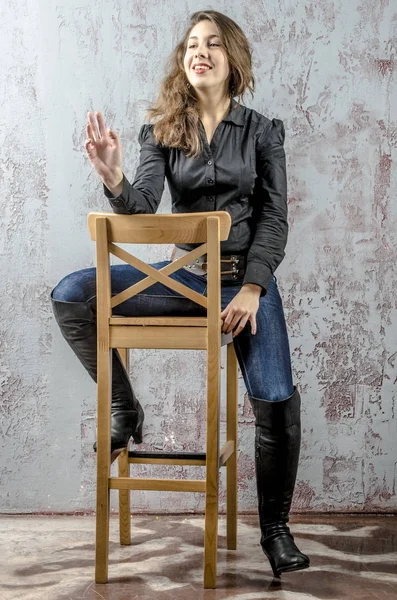 Young girl with curly hair in a black shirt, jeans and high boots cowboy western style — Stock Photo, Image