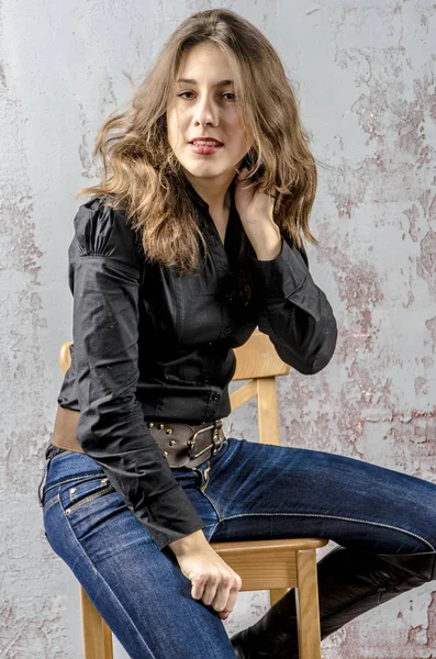 Jovem com cabelo encaracolado em uma camisa preta, jeans e botas de alta cowboy estilo ocidental — Fotografia de Stock