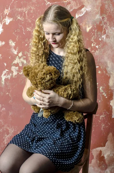 Gadis pirang muda dengan rambut panjang keriting dalam gaun polka-dot dengan boneka beruang — Stok Foto