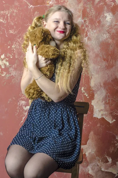 Bir benekli kıvırcık uzun saçlı genç sarışın kız elbise oyuncak ayı ile — Stok fotoğraf