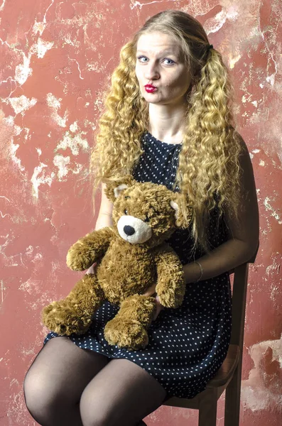 Νεαρή ξανθιά κοπέλα με σγουρά μακριά μαλλιά σε ένα πουά φόρεμα με αρκουδάκι — Φωτογραφία Αρχείου