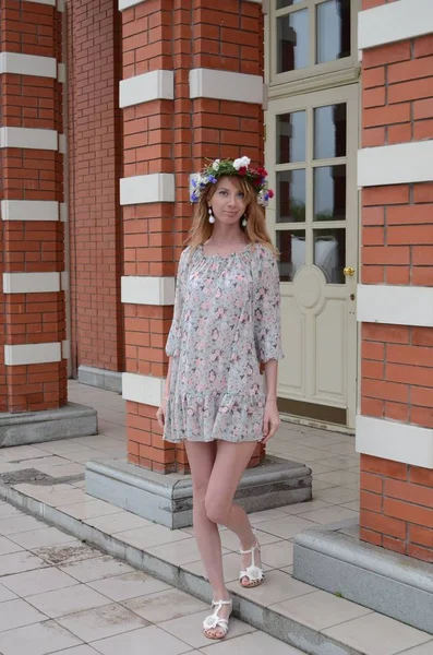 Uma menina com cabelos longos em uma coroa de flores e um vestido de verão — Fotografia de Stock